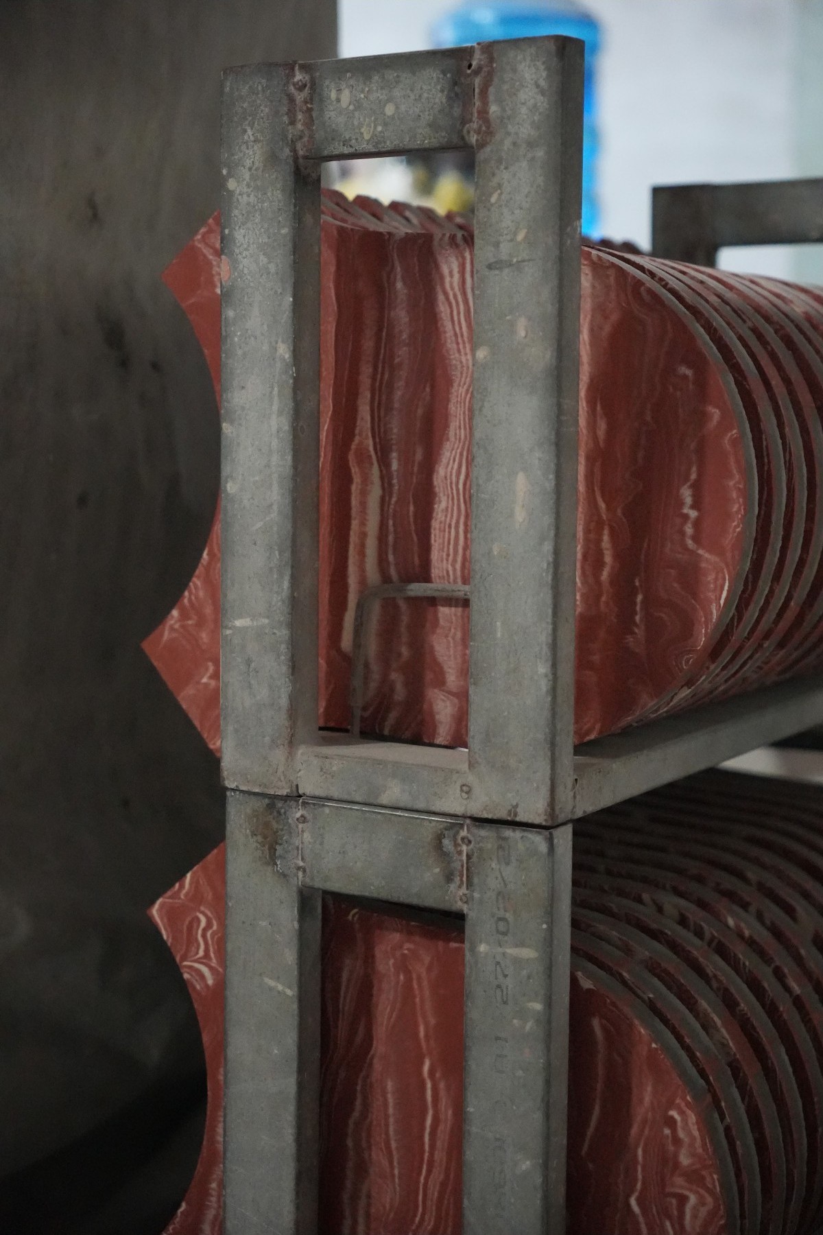 Baldosas hidráulicas recién prensadas secando en bastidores metálicos en la fábrica de Mosaics Torra